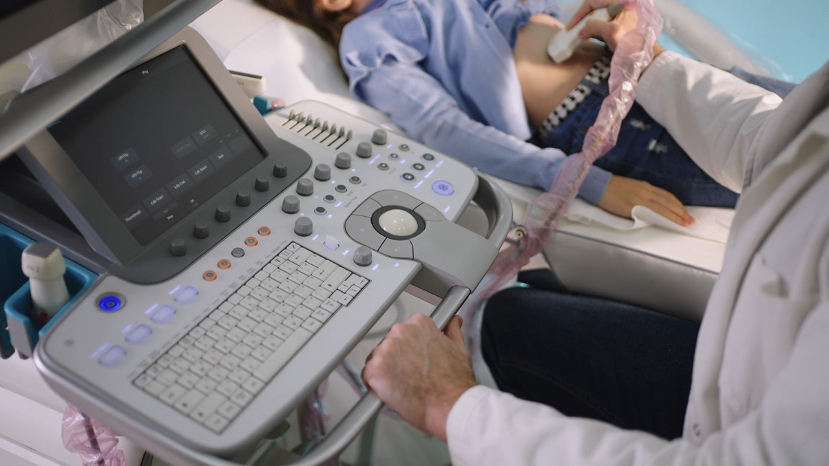 Doktor obavlja ultrazvučni pregled abdomena pacijentkinje dok se prikaz vidi na ekranu aparata