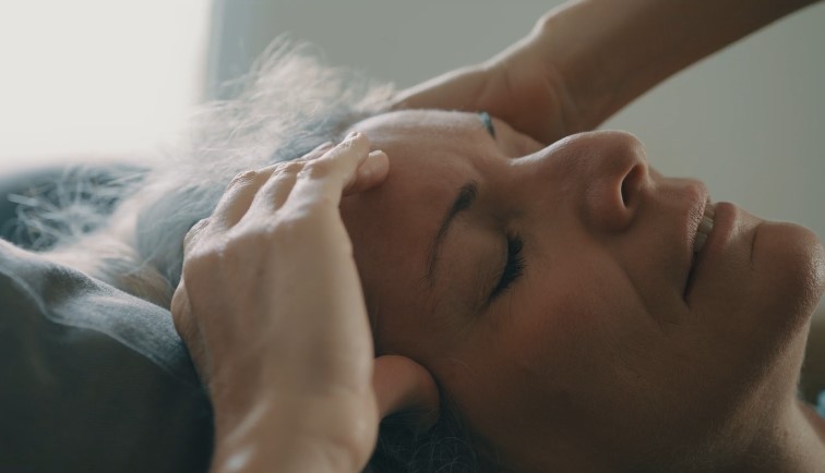 Žena leži na leđima s rukama na glavi