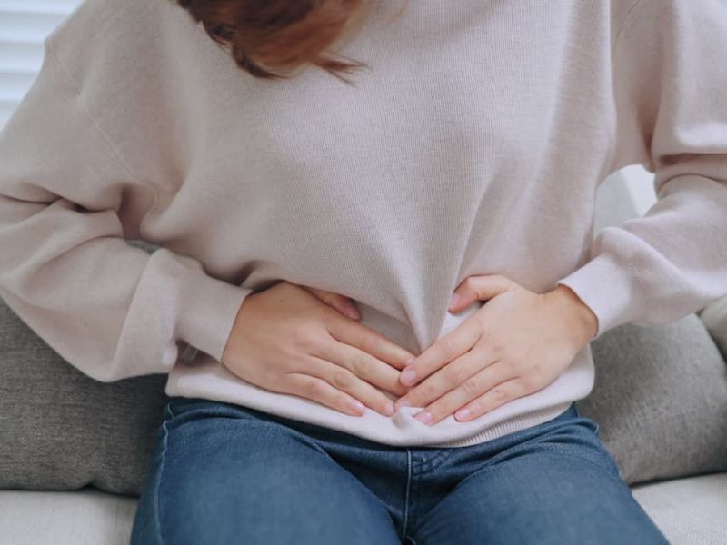devojka se drži za stomak od bola