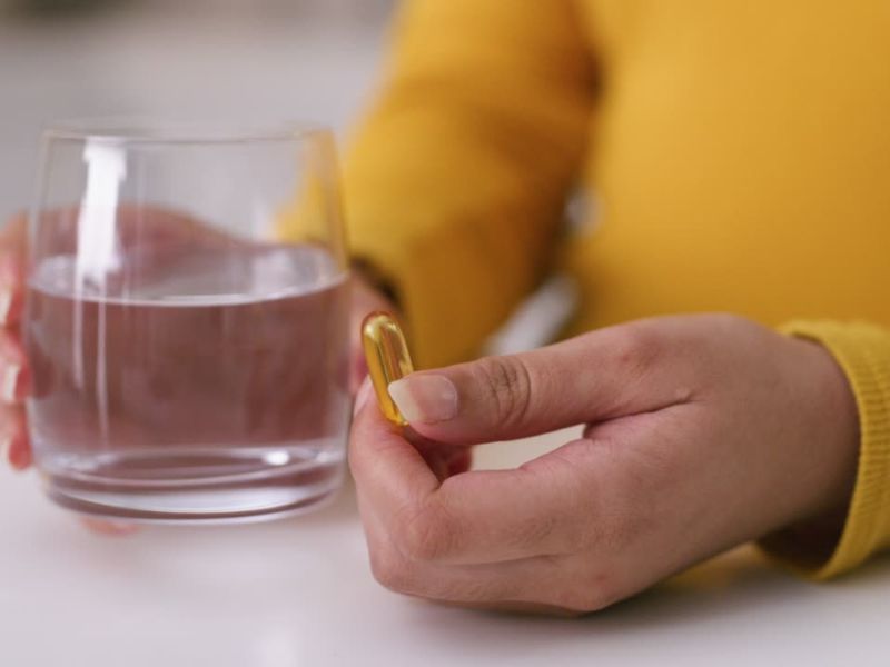 osoba drži suplement i čašu vode u ruci