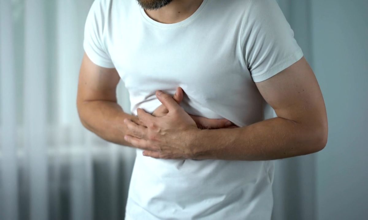 muška osoba se drži za stomak od bola