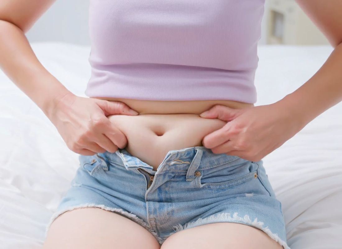 devojka hvata svoje salo na stomaku