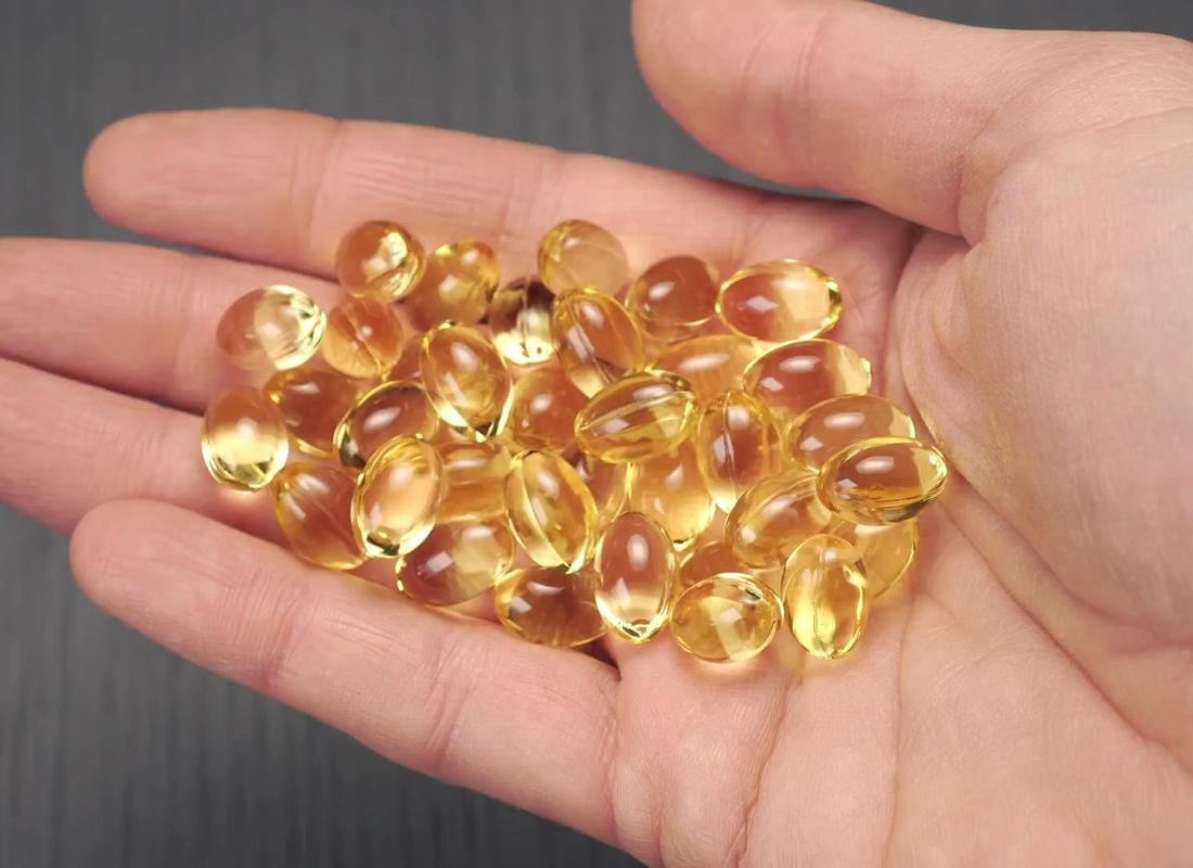 osoba drži na dlanu omega 3 tablete