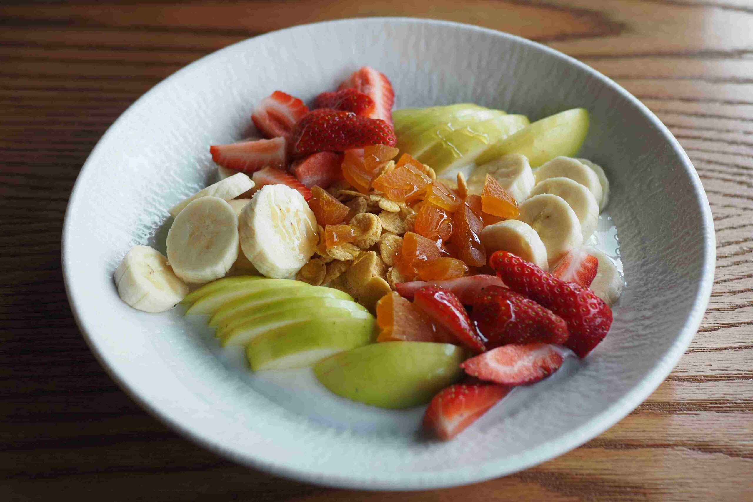 Činija sa jogurtom, voćem i žitaricama na drvenom stolu