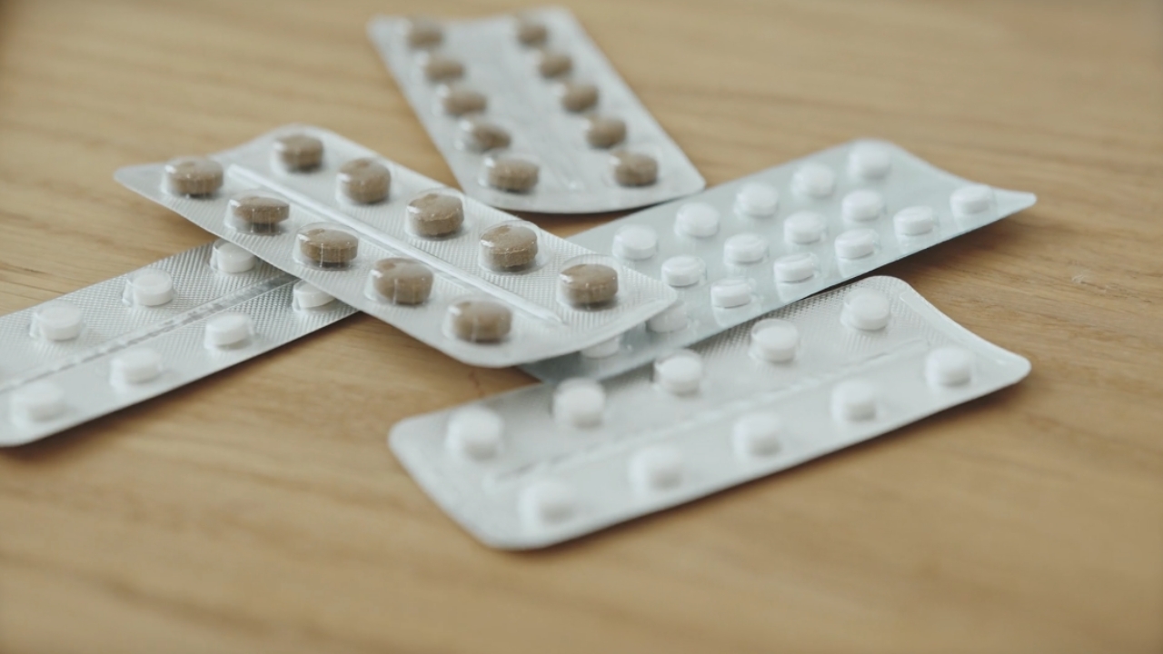 Više blistera sa tabletama nalazi se na drvenom stolu